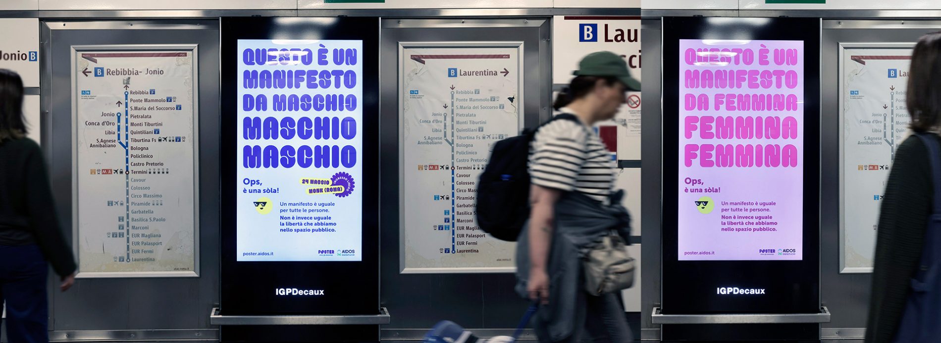 immagine di due monitor in metropolitana a Roma che visualizzano la campagna nei due soggetti "da maschio" e "da femmina", in uno la scritta "questo manifesto è da maschio", nell'altro "questo manifesto è da femmina"